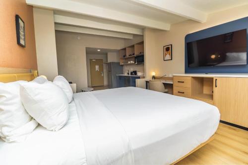 a bedroom with a large white bed and a flat screen tv at Ramada by Wyndham Davenport Orlando South in Davenport