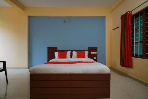a bedroom with a large bed with red pillows at Hotel O Greenland in Meppādi