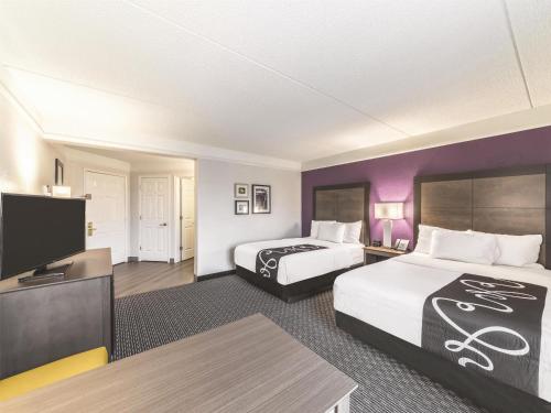 a hotel room with two beds and a flat screen tv at La Quinta by Wyndham Austin Airport in Austin