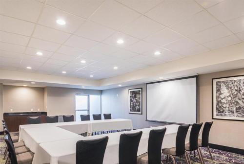 a conference room with tables and chairs and a screen at La Quinta by Wyndham Austin Airport in Austin