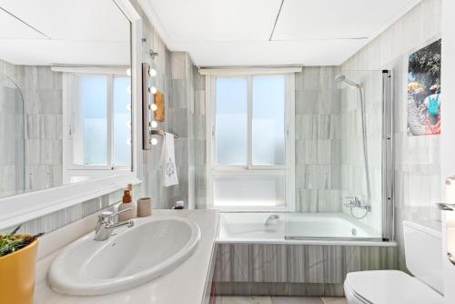 a white bathroom with a tub and a sink at Apartamento del Mar in Marbella