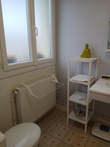 La salle de bains est pourvue de toilettes, d'un lavabo et d'une étagère. dans l'établissement Le Courteline, à Castres