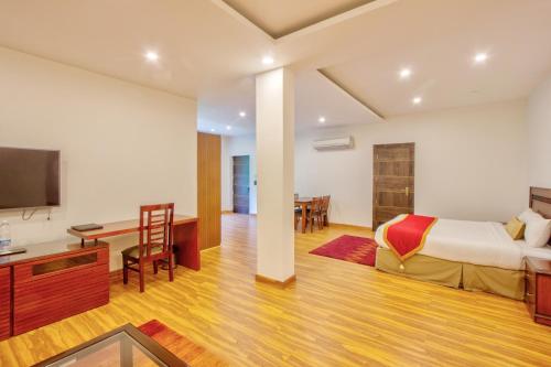 a bedroom with a bed and a desk and a tv at Span Inn & Suites - Manali in Baragrān
