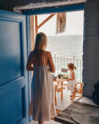 a woman looking out of a window at the ocean at Rocksecret Edge in Kalamata