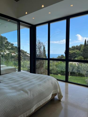 - une chambre avec un lit et de grandes baies vitrées dans l'établissement La perle - villa de luxe, à Villefranche-sur-Mer