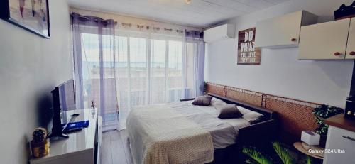 une chambre avec un lit et une grande fenêtre dans l'établissement Studio 2 personnes Vue Mer Climatisé Linge Maison, au Lavandou