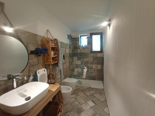 Un baño con lavabo, inodoro y espejo. en Da Elias, en Budoni