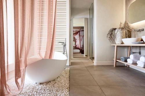 a bathroom with a white tub and a shower at Amazon Mykonos Suites & Spa in Agios Ioannis Mykonos