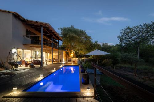 a swimming pool with lights next to a house at Rafiki Bush Lodge in Hoedspruit