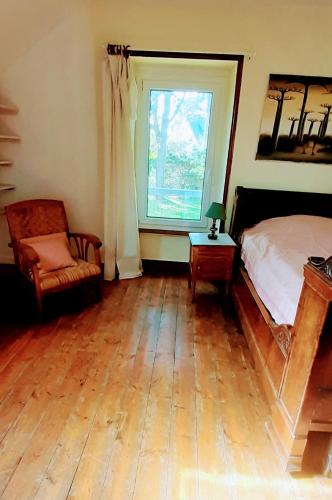 une chambre avec un lit, une chaise et une fenêtre dans l'établissement Résidence Keryvet, maison de charme vue mer, plage à 250m,, à Pleumeur-Bodou