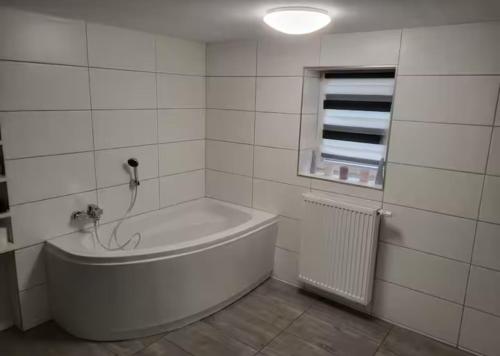bagno bianco con vasca e finestra di Schöne Ferienwohnung nähe Geiseltalsee a Bad Lauchstädt