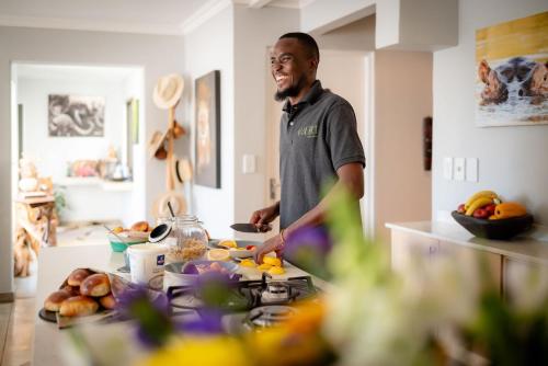 a man standing in a kitchen preparing food at Rafiki Bush Lodge in Hoedspruit
