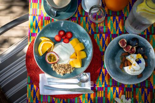 a table topped with two plates of food with fruit at Rafiki Bush Lodge in Hoedspruit