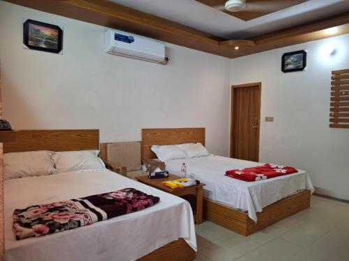 una camera da letto con due letti e un tavolo con gonne da letto di Hotel Dhanmondi a Dhaka