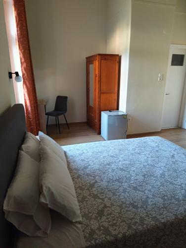 a bedroom with a bed and a chair and a cabinet at Anesis Hotel in Loutra Edipsou
