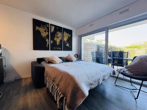 une chambre avec un lit et une grande fenêtre dans l'établissement Ty Cardinaux, grand studio cabine, terrasse, jardin, tennis, à Quiberon