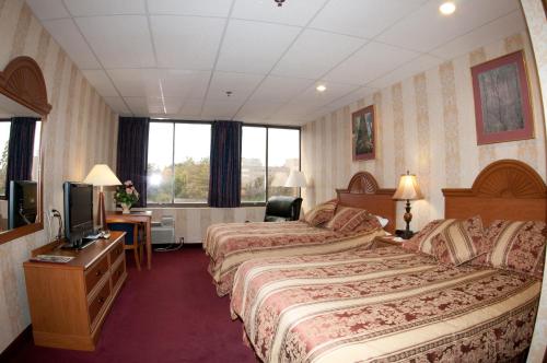una camera d'albergo con due letti e una televisione di Amsterdam Hotel a Stamford