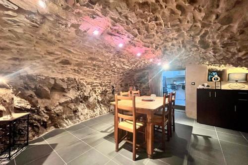 une salle à manger avec une table et un mur en pierre dans l'établissement Blondel - Saint Jean de Muzols, à Saint-Jean-de-Muzols