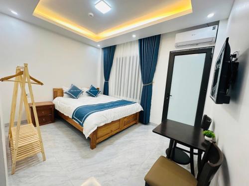 a bedroom with a bed and a television and a desk at New Sun Hotel in Dồng Văn