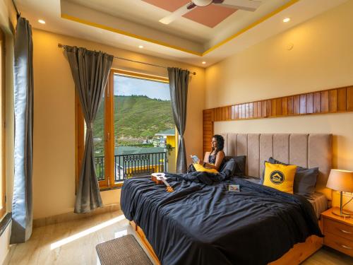 a woman sitting on a bed in a bedroom at The Hosteller Chakrata in Chakrāta