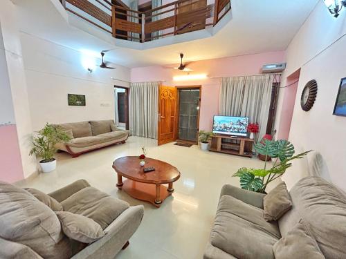 特里凡得琅La Casa Trivandrum 4 BHK AC Luxury Villa at City Centre, Just 5 kms from Airport & 3 Kms to Trivandrum Railway Station的带沙发、桌子和电视的客厅