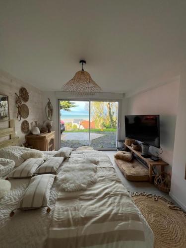 un grand lit dans une chambre avec une grande fenêtre dans l'établissement Les Collines d'Omaha, à Saint-Laurent-sur-Mer