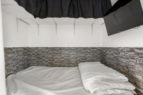 un lit dans une chambre avec un mur de briques dans l'établissement Résidence Dom - 3min à pied de la Plage, au Cap d'Agde