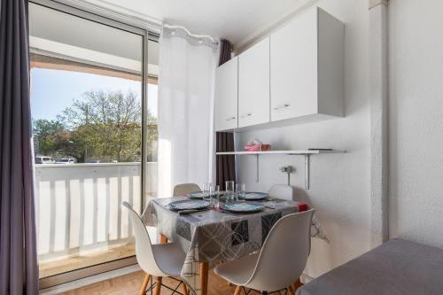 une salle à manger avec une table et des chaises et une fenêtre dans l'établissement Résidence Dom - 3min à pied de la Plage, au Cap d'Agde