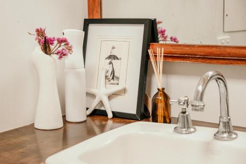 a counter with vases and a picture and a sink at The Wandering Whale Port Fairy in Port Fairy