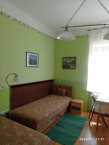 a bedroom with a bed in a room with green walls at Kápolnás Vendégház Báta-Gemenc in Báta