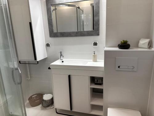 a white bathroom with a sink and a mirror at Przytulny Apartament z Balkonem Stalowa Wola in Stalowa Wola