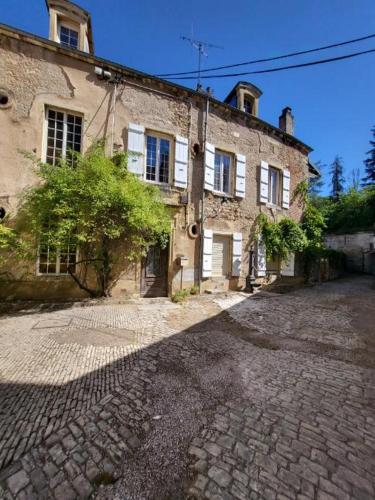 - un vieux bâtiment en pierre sur une rue pavée dans l'établissement Maison style Haussmannien centre ville, à Gray