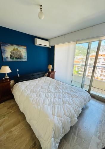 une chambre avec un grand lit avec un mur bleu dans l'établissement Appartement Menton front de mer au dernier étage de 95M2 avec Terrasse de 70M2, à Roquebrune-Cap-Martin