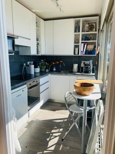 - une cuisine avec des placards blancs et un bol sur une table dans l'établissement Appartement Menton front de mer au dernier étage de 95M2 avec Terrasse de 70M2, à Roquebrune-Cap-Martin