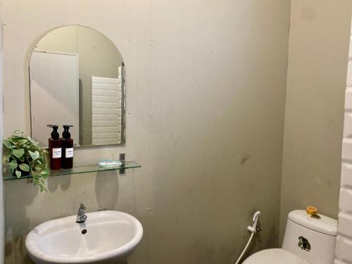 a bathroom with a sink and a mirror and a toilet at Nokhook House in Trang
