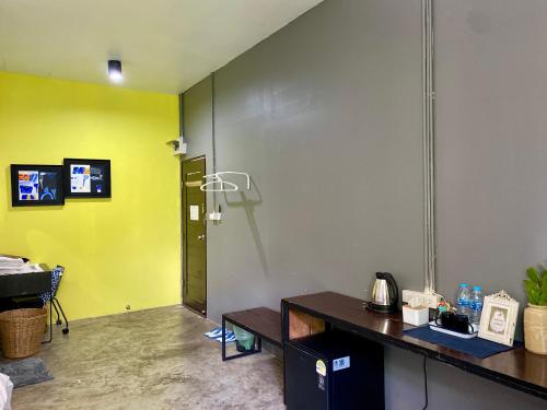 a room with a desk and a yellow wall at Nokhook House in Trang