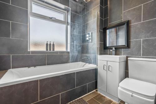a bathroom with a tub and a toilet and a window at The Bishopsworth House in Bristol