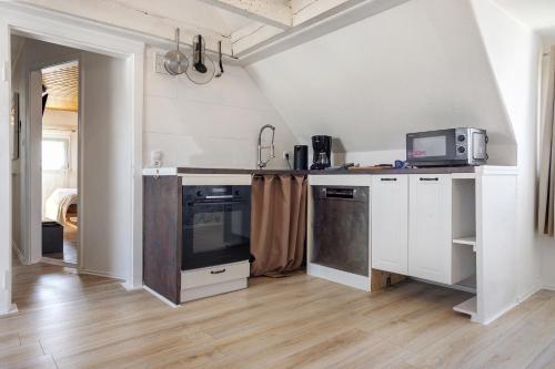 a kitchen with white cabinets and a tv on a counter at Ferienwohnung Fischerhaus in Wasserburg am Bodensee