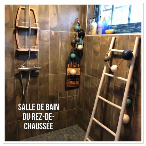 une salle de bain avec deux échelles en bois et un mur avec des boules dans l'établissement Les Jardins d'Omaha, à Saint-Laurent-sur-Mer