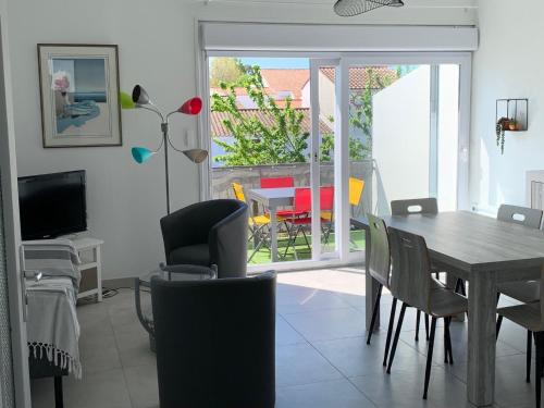 une salle à manger avec une table, des chaises et une télévision dans l'établissement Maison familiale, à La Tranche-sur-Mer