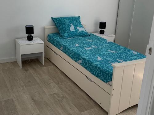 - un lit avec une couette bleue et 2 tables de chevet dans l'établissement Maison familiale, à La Tranche-sur-Mer