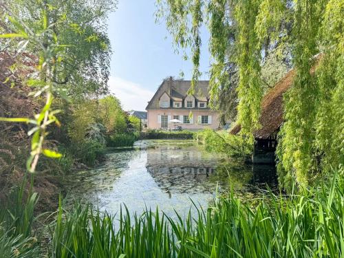 a house and a pond in front of a house at La Meslaysienne - Comfortable house, swimming pool in Meslay-le-Vidame