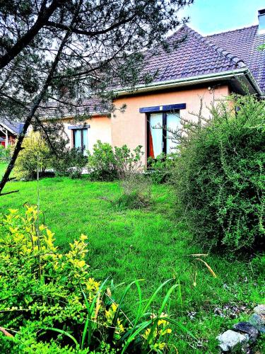 une maison avec une cour avec de l'herbe verte dans l'établissement PEACE & PINK Maison zen & Cocon stylé a 5 mn des vagues de Wimereux, à Maninghen-Henne