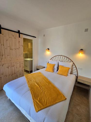 une chambre avec un grand lit blanc avec des oreillers orange dans l'établissement Les Saladelles, à Saintes-Maries-de-la-Mer