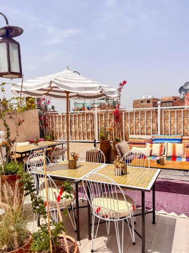 a patio with tables and chairs and an umbrella at Riad 10 Mandarin BOUTIQUE RIAD in Marrakesh
