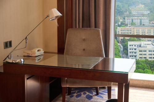 a desk with a lamp and a chair and a window at Wyndham Grand Plaza Royale Chenzhou in Chenzhou