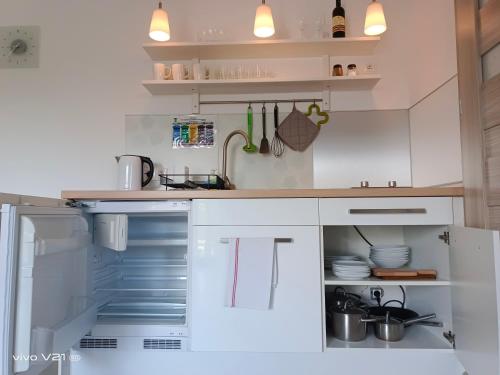 a kitchen with white cabinets and an open refrigerator at Villa Cork in Dębki