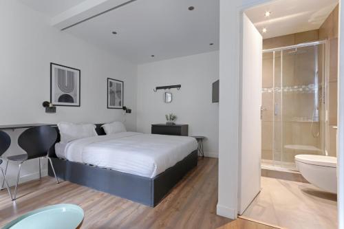 - une chambre blanche avec un lit, une baignoire et un lavabo dans l'établissement TBS 306 - Lovely studio in Paris, à Paris