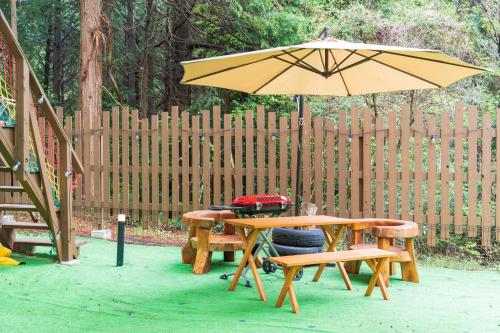 a picnic table with an umbrella and two benches at 小路裏園 Kojiuraen in Kannami