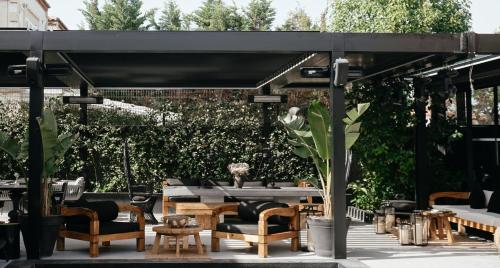 a patio with tables and chairs under a black canopy at The Local House Alaçatı in Alacati